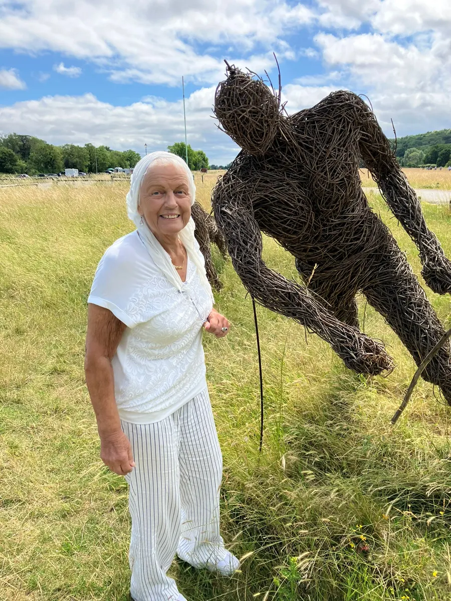 Linda beside a willow sculpture in a meadow