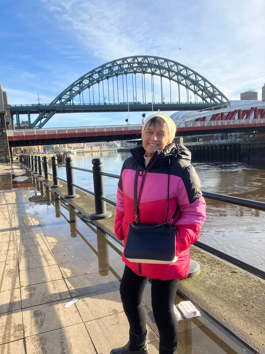 Linda beside the river with the Tyne Bridge behind her