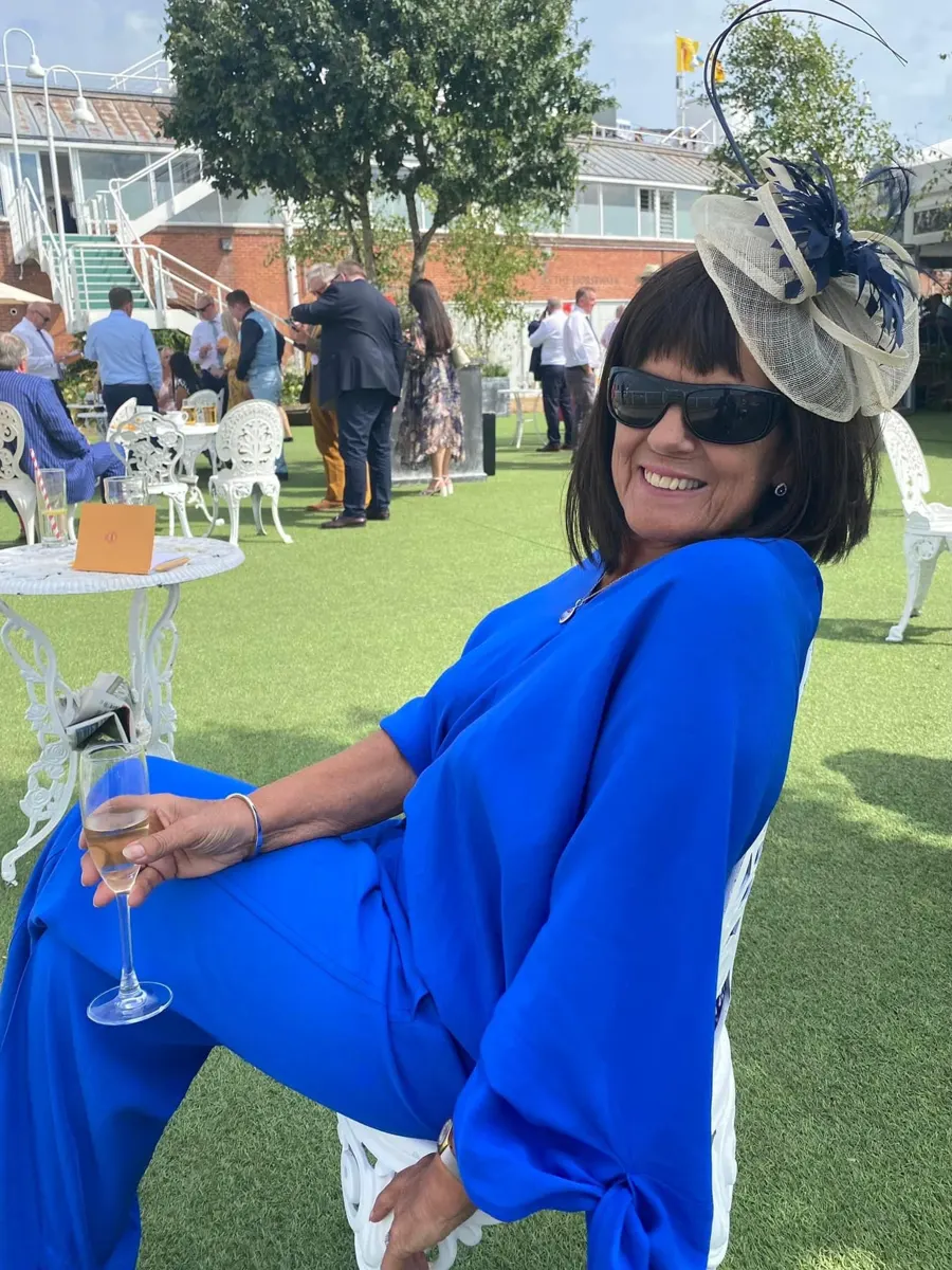 Linda in a fascinator relaxing on the lawn at the races